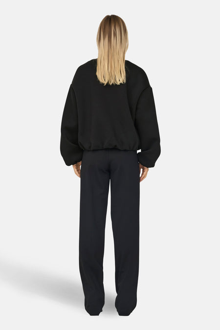 Zwarte korte jas van ONLY, gezien van achteren, gecombineerd met een zwarte broek.