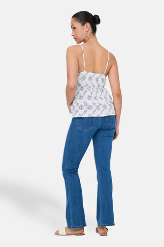 Witte mouwloze blouse van ONLY, met bloemenmotief, gecombineerd met blauwe jeans en sandalen.