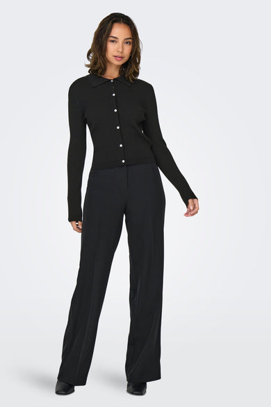 Zwarte trui van ONLY, met lange mouwen en knoopsluiting, gecombineerd met een zwarte pantalon en zwarte schoenen.