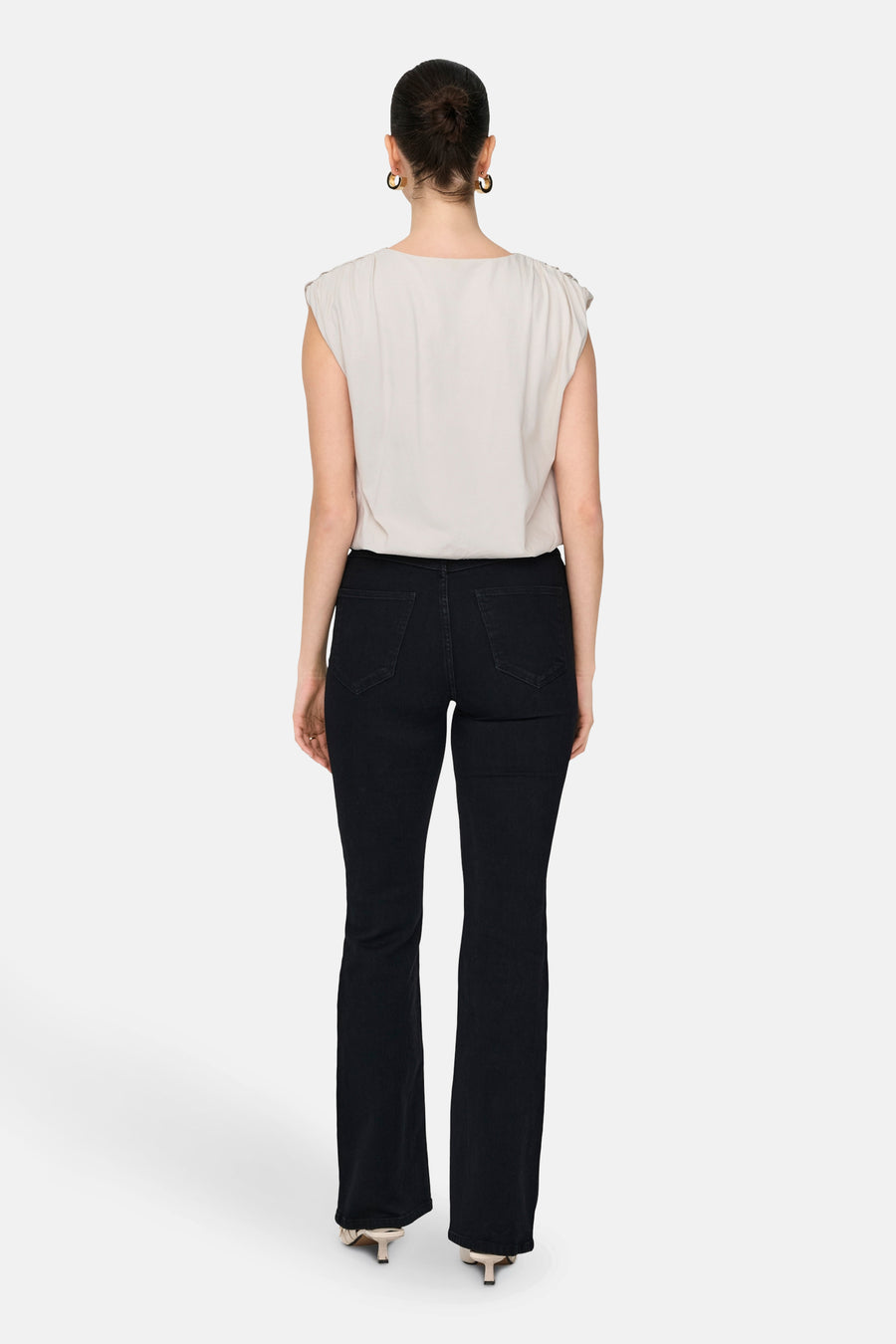 Witte top van JDY, gezien van achteren, gecombineerd met donkere jeans en gouden oorbellen.