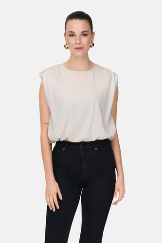 Witte mouwloze top van JDY, gedragen met zwarte jeans en gouden oorringen.