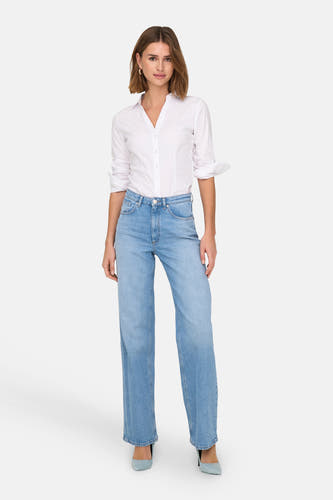 Wijd uitlopende lichtblauwe jeans van ONLY, met een subtiele wassing en gedragen met een wit overhemd en blauwe hakken.

