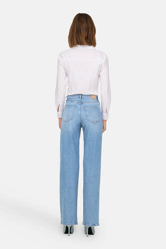 Lichtblauwe, wijde jeans van ONLY, met een witte blouse en zwarte pumps.