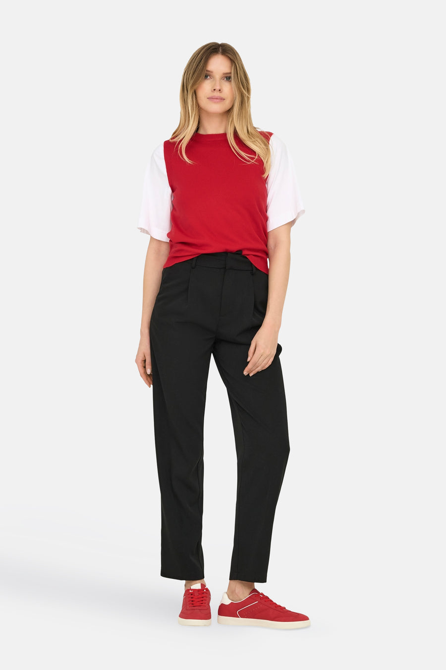 Rode debardeur van ONLY®, gecombineerd met een wit shirt, een zwarte pantalon en rode sneakers.

