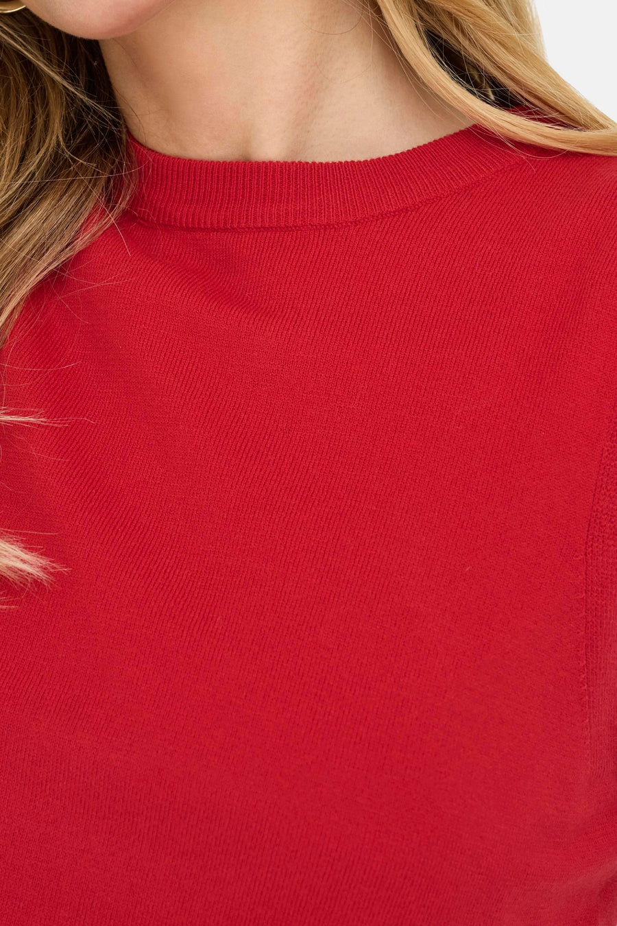 Rode top van ONLY®, close-up van de textuur en halslijn, met een vleugje blond haar.
