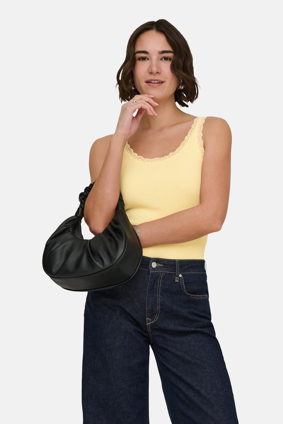 Haut côtelée jaune de ONLY avec finition en dentelle, portée avec un jean évasé, des mules marron et un sac à main noir.
