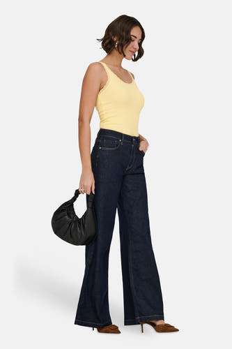 Gele geribbelde top van ONLY met kanten afwerking, gedragen met flared jeans, bruine muiltjes en zwarte handtas.