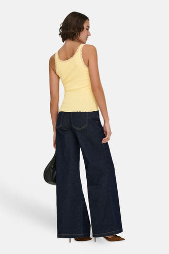 Haut côtelé jaune de ONLY avec finition en dentelle et ourlet ondulé, porté avec un jean foncé vu de dos.