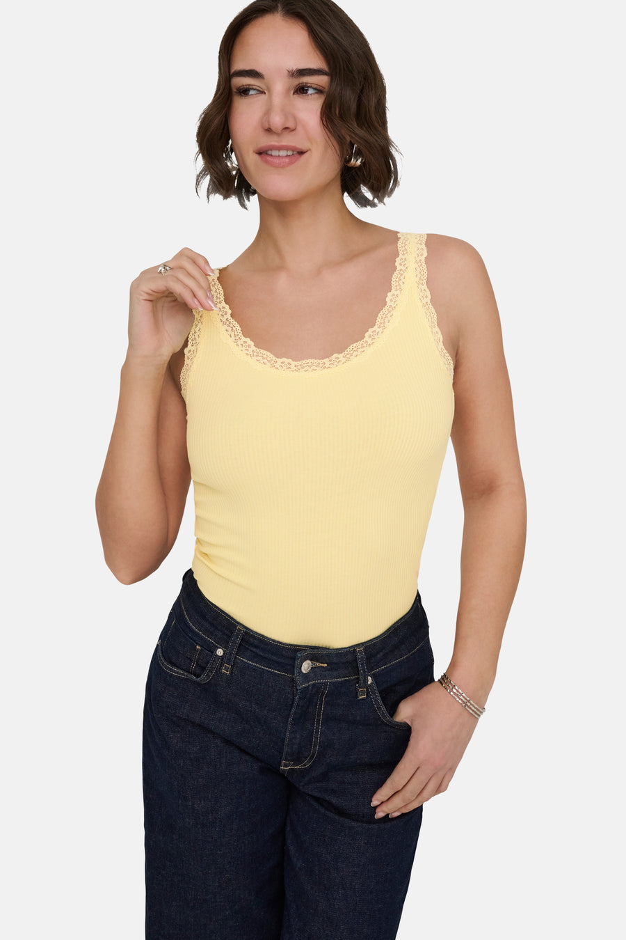 Haut côtelé jaune de ONLY® avec finition en dentelle le long de l'encolure et des bretelles, porté avec un jean bleu foncé.