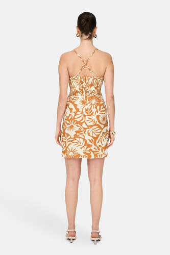 Mouwloze oranje jurk van ONLY, met bruin-wit bloemenpatroon en gekruiste bandjes op de rug.
