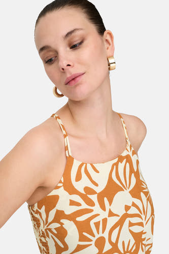Oranje mouwloze jurk van ONLY, met een beige bladerpatroon en goudkleurige oorringen.
