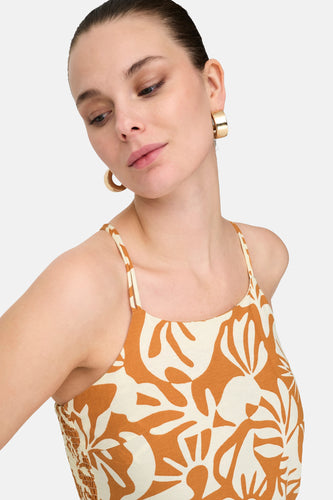 Oranje mouwloze jurk van ONLY, met een beige bladerpatroon en goudkleurige oorringen.