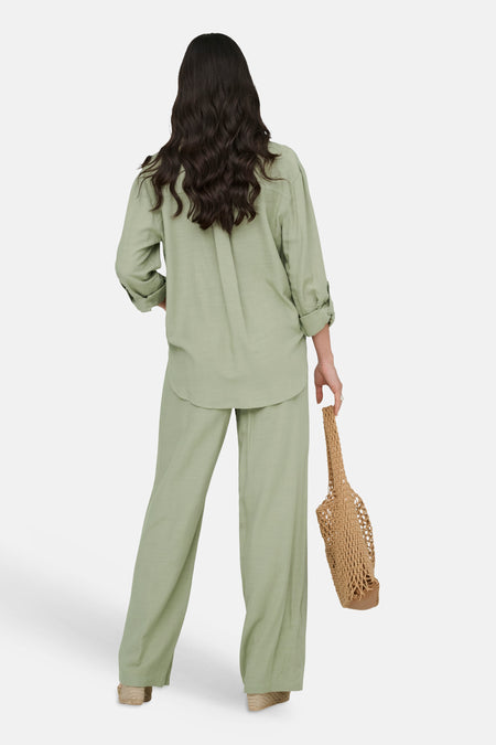 Groen overhemd met lange mouwen van JDY, gedragen met bijpassende broek, van achteren gezien, met een geweven tas.