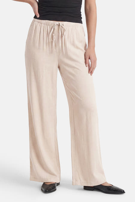 Ecru broek van JDY met elastische taille, trekkoord en wijde pijpen, gedragen met een zwarte top en schoenen.