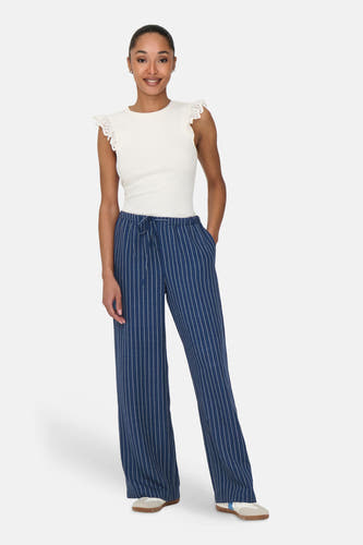 Blauwe broek van JDY, met krijtstreep en trekkoord in de taille, gedragen met een witte top.
