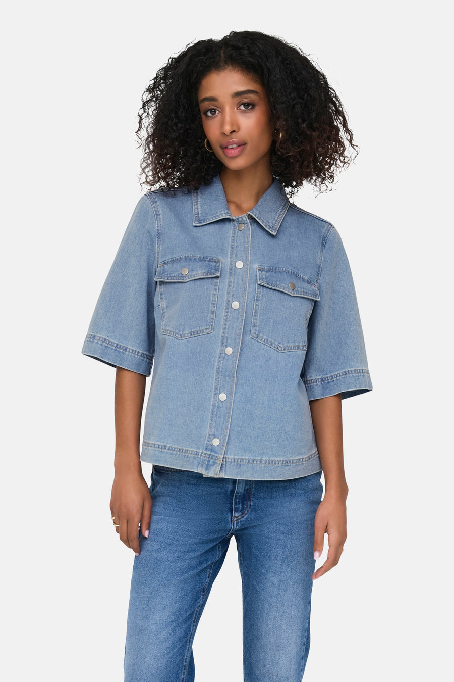 Chemise en jean bleu clair à manches courtes de ONLY, avec poches poitrine et portée avec un jean et des talons bleus.