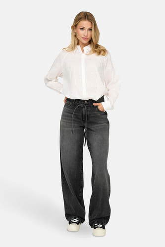 Donkergrijze rechte jeans van ONLY, gedragen met een witte blouse met zilveren accenten en sneakers.