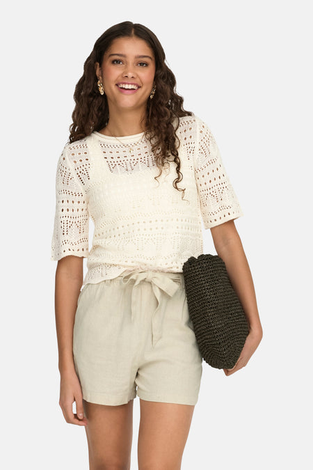 Ecru trui met ronde hals van JDY, met ajourpatroon en gedragen met beige linnen shorts.