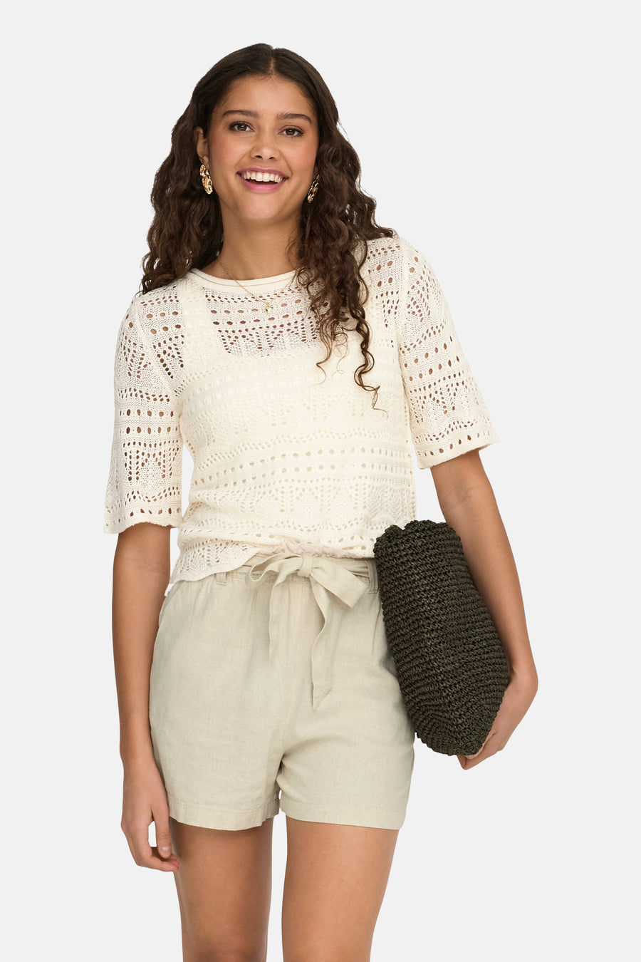 Pull écru à col rond de JDY, avec motif ajour et porté avec un short en lin beige.