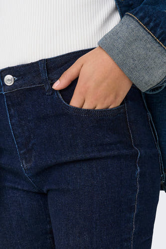 Jean flare bleu marine d'ONLY, avec la main dans la poche et une veste en denim.