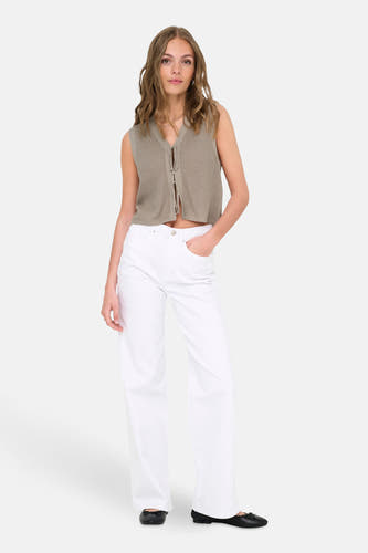 T-shirt sans manches beige ONLY, avec des cordons décoratifs et associé à des jeans blancs et des chaussures noires.
