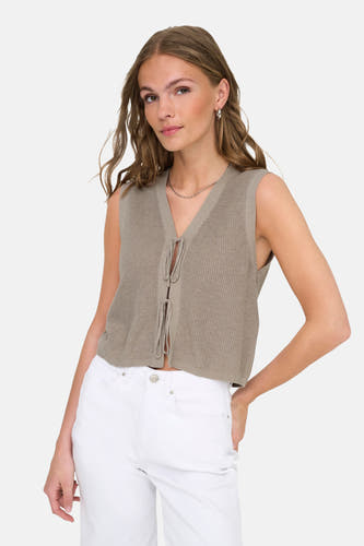 Top beige sans manches ONLY, avec détail de bouton et porté avec une chaîne d'argent et un pantalon blanc.