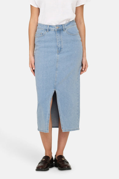 Lange lichtblauwe denim rok van JDY, met een split aan de voorkant en donkere leren schoenen.
