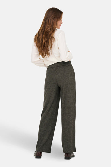 Pantalon brun de ONLY, avec une texture subtile et des jambes larges, associé à une blouse blanche et des chaussures brunes, vu de dos.