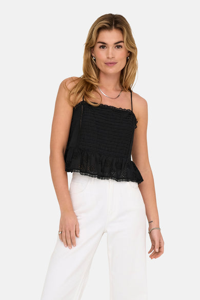 Blouse noire sans manches d'ONLY, avec des plis et un bord en dentelle, associée à une jupe blanche.
