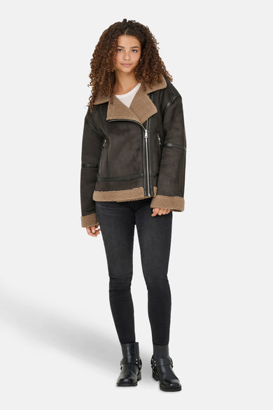 Bruine korte jas van ONLY, met teddy voering, gedragen met zwarte jeans en laarzen.
