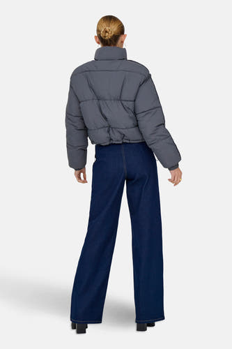 Grijze korte jas van ONLY, met brede donkerblauwe jeans en zwarte schoenen.