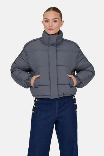 Grijs korte jas van ONLY, met steekzakken en gecombineerd met een donkerblauwe broek.
