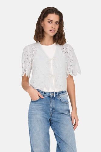 Witte blouse met korte mouwen van ONLY, afgewerkt met broderie en gecombineerd met een wit t-shirt en blauwe jeans.

