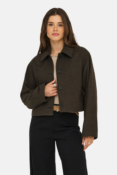 Manteau court brun d'ONLY avec fermeture à boutons, porté sur une chemise beige et un pantalon noir.