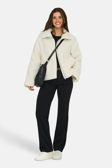Manteau court blanc d'ONLY, avec des poches de épaules noires, un pantalon noir et des baskets blanches.
