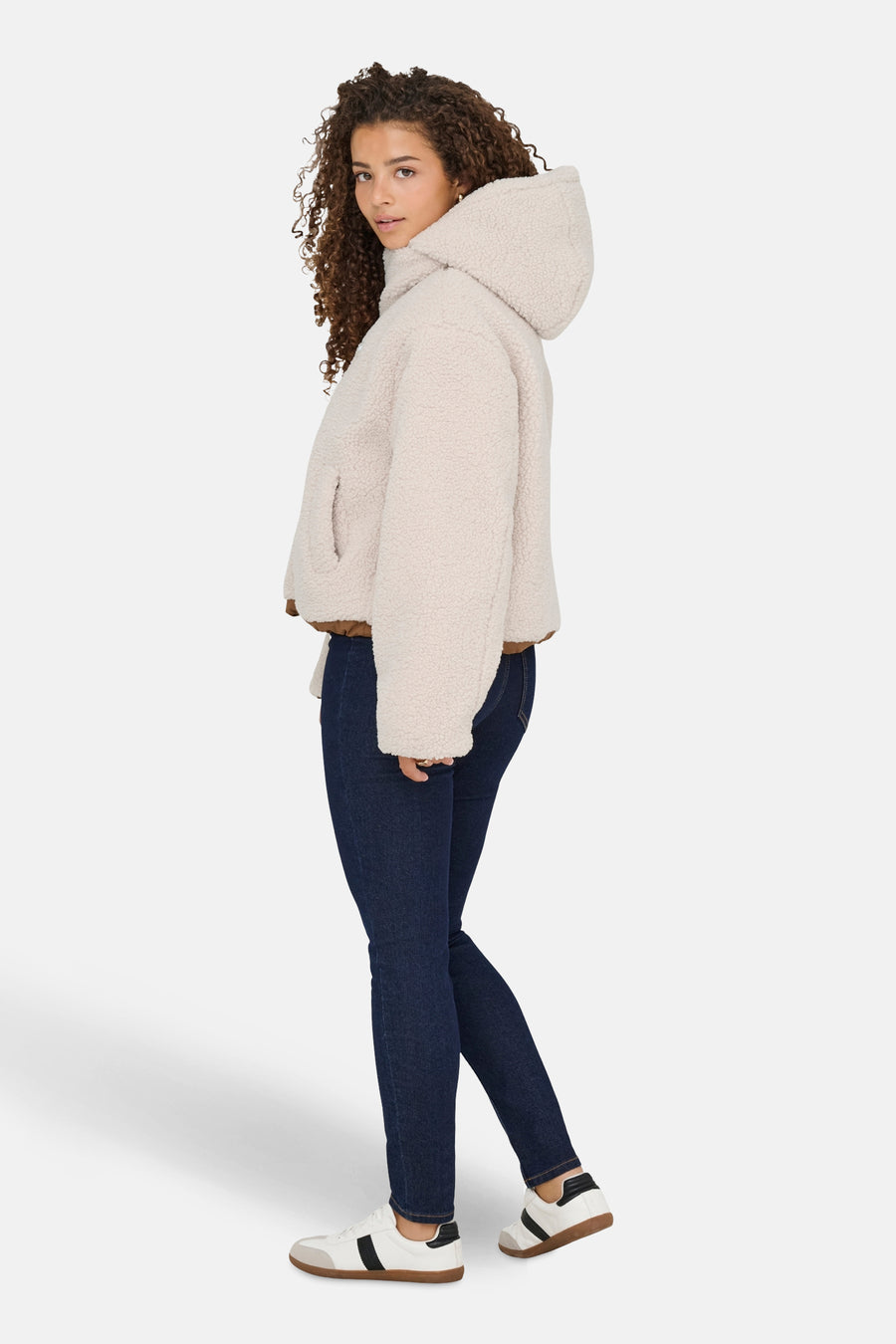Ecru jas van ONLY, met een capuchon, gecombineerd met donkere jeans en witte sneakers.
