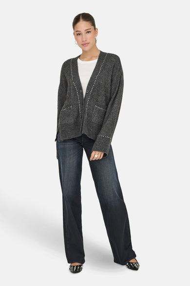 Cardigan gris d'ONLY, terminé avec des strass, porté sur un t-shirt blanc et des jeans foncés avec des strass sur les chaussures.