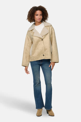 Ecru jas van ONLY, met sherpadetails, gecombineerd met een wit shirt, jeans en suède laarzen.
