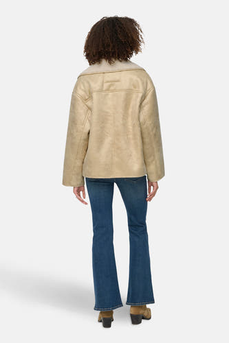 Ecru korte jas van ONLY, met een lammy kraag en gedragen met een blauwe jeans.
