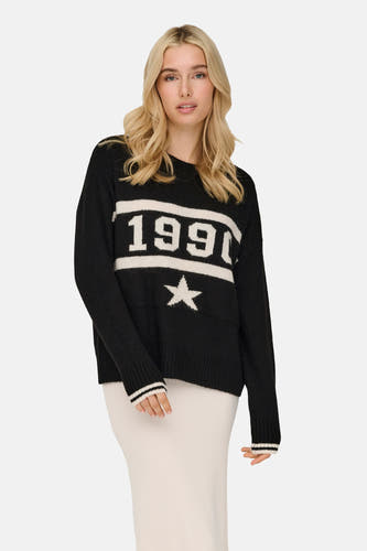 Zwarte trui met ronde hals van ONLY, met witte cijfers en een ster, gecombineerd met een crèmekleurige rok.
