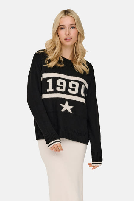 Zwarte trui met ronde hals van ONLY, met witte cijfers en een ster, gecombineerd met een crèmekleurige rok.
