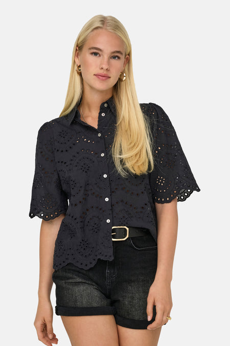 Chemise noire de ONLY, avec détails brodés et manches courtes, combinée avec une ceinture noire et un short en jean.