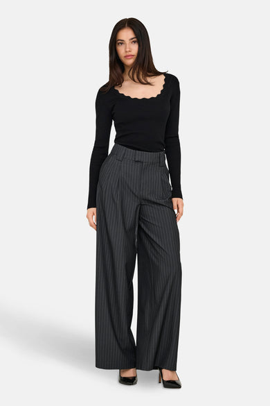 Pantalon gris d'ONLY avec une rayure de craie et des jambes larges, associé à un haut noir et des baskets noires.