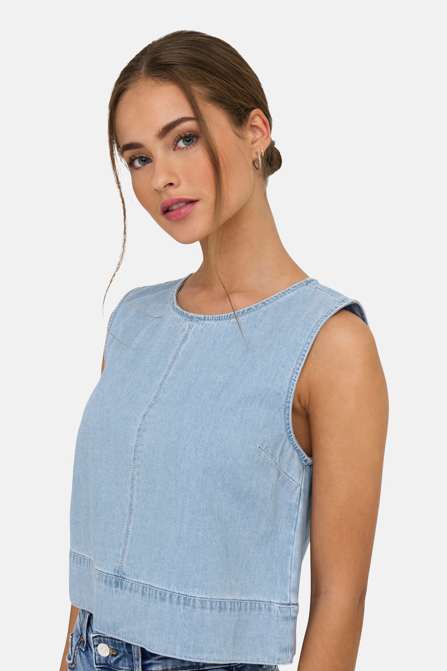 Jonge vrouw met blauwe denim top, close-up, neutrale achtergrond.
