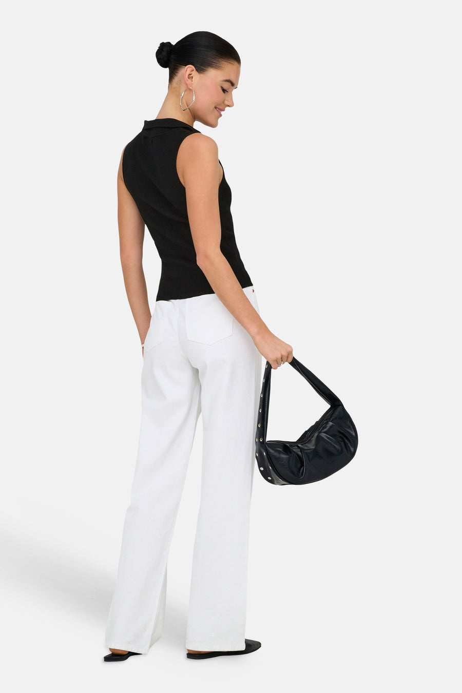 Haut noire sans manches de JDY, avec un col montant, combiné avec un pantalon blanc et un sac à main noir.