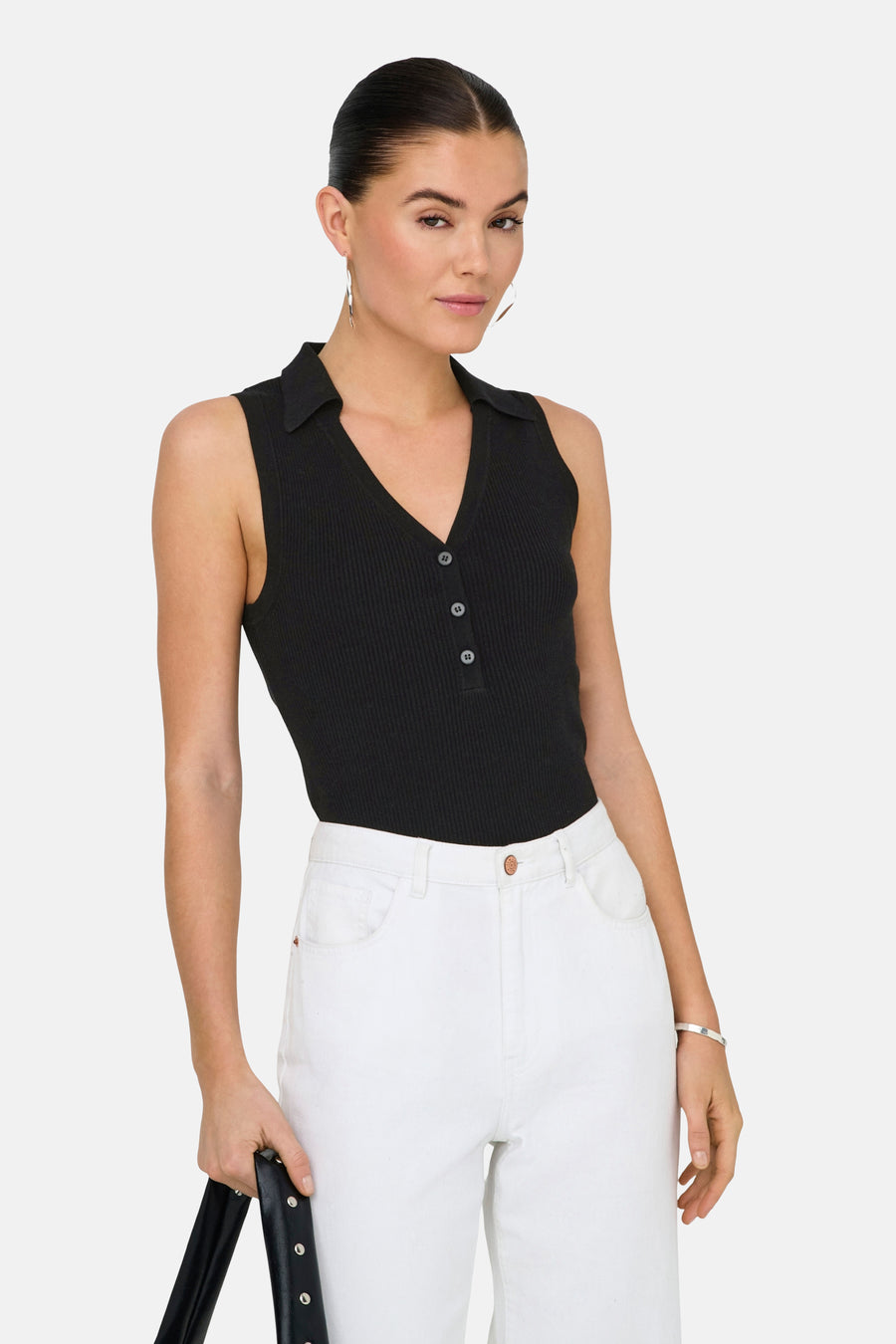 Haut noir sans manches de JDY, avec col et fermeture à boutons, combiné avec un pantalon blanc.