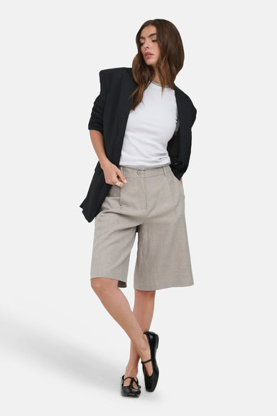 Beige short van ONLY® met weefstructuur, plooien en knielengte, gestyled met een zwarte blazer en witte top.