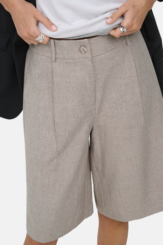 Beige short van ONLY® met lichte textuur, plooien en knoopsluiting, gedragen met wit topje en zwarte blazer.