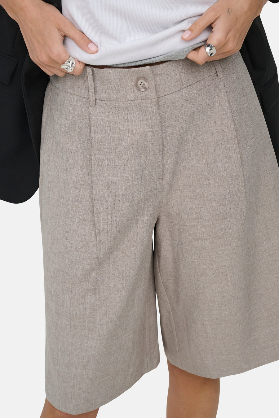 Beige short van ONLY® met lichte textuur, plooien en knoopsluiting, gedragen met wit topje en zwarte blazer.