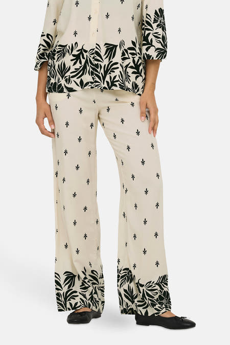 Ecru broek van JDY met een bladpatroon en brede pijpen, gedragen met een bijpassende blouse.
